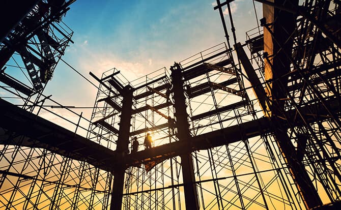 Construction scaffolding silhouetted against a golden sunset